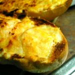 One half of a French bread loaf covered in melted cheese and mayo