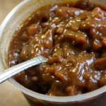 A container of Boston baked beans with a spoon