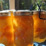 Sunlight through jars of peaches. On the far right, one of the cans has a blue can lifter holding the top