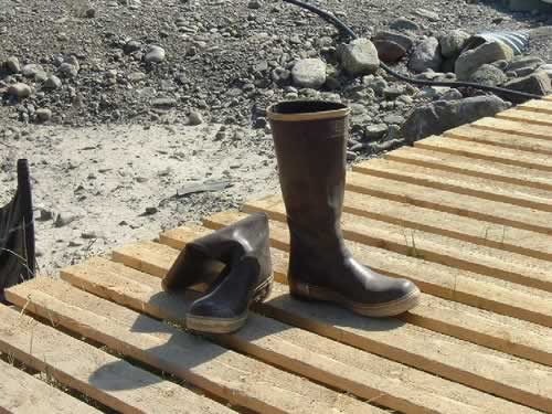 A pair of black and yellow fisherman's boots sitting on a dock