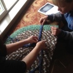 Two women working on a braided rug