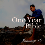 Man sitting on rocky cliff reading a Bible