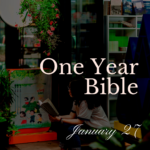 Woman reading Bible on the sidewalk in front of a sstore