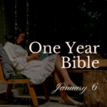 Girl in white ruffle dress sitting on a bench reading her Bible. Droplets of rain are falling in the forefront.