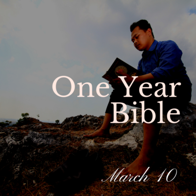 Man sitting on a hill reading a Bible