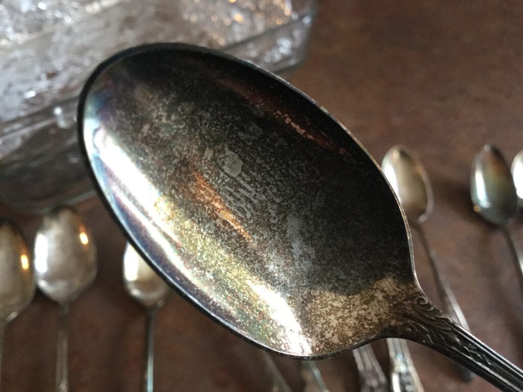 A spoon in the foreground showing tarnish