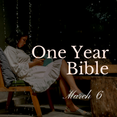 Girl in white dress sitting on a chair reading a Bible