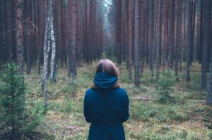Woman standing in front of a path through he woods